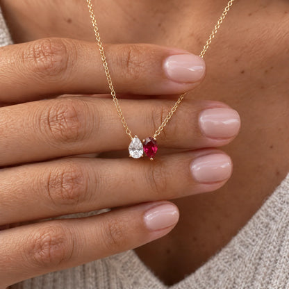 Collar Raíces con dos piedras de nacimiento sobre una mano